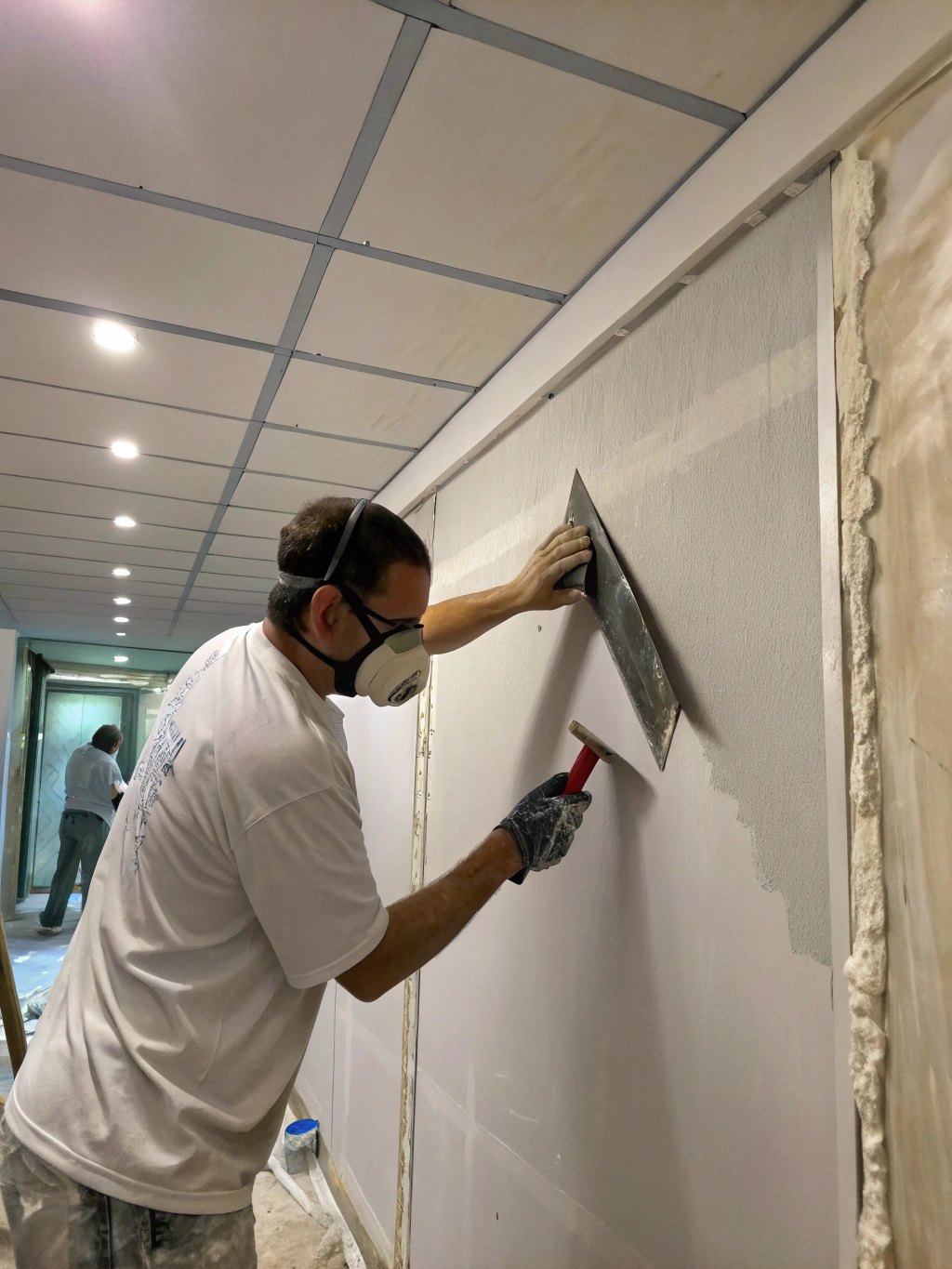Technician performing a precise drywall finish with professional tools in a well-lit construction site